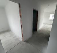 A hallway with white walls and a concrete floor in a family house.