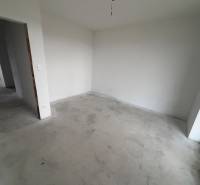 Empty room in a family house with white walls and a concrete floor.