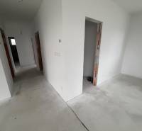 A hallway in a family house with white walls and a concrete floor.