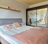 A bedroom in a two-room apartment with a mirrored wardrobe and an upholstered bed.