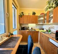A kitchen in a studio apartment with wooden cabinets and a dining table.