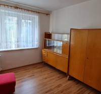 A room in a three-room apartment with older furniture and a wooden-patterned floor.