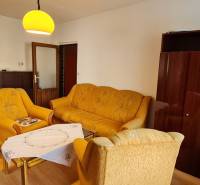 A living room in a three-room apartment with brown furniture and yellow sofas.