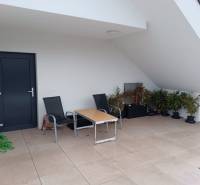 A balcony in a 2-room apartment with a terrace, chairs, and plants.