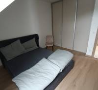 Bedroom in a two-room apartment with a bed and a wardrobe, floor with wooden decor.