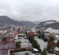 Winter panorama of Nová Baňa from Pod sekvojou street with snow-covered hills and roofs.