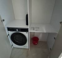 In the 2-room apartment, there is a washing machine in the storage space and a red bucket.