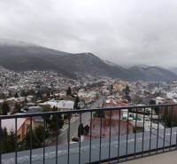 View of the snowy town of Nová Baňa from Pod sekvojou Street with a mountain panorama.