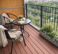 A balcony with a wooden decor floor, a table, chairs, and a view of nature.
