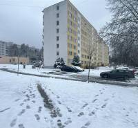 A winter scene on Bazovského Street in Zvolen with an apartment building and parked cars.