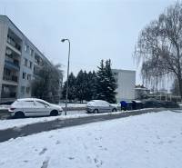 Winter street Bazovského in Zvolen with snow-covered cars and trees, apartment building in the background.