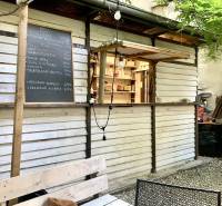 Exterior of a gastro space on Sedlárska Street in Bratislava with a menu and wooden seating.