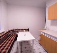 A kitchen in a 2-room apartment with seating and white tiles on the floor.