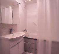Bathroom in a 2-room apartment with a sink, mirror, bathtub, and white tiles.