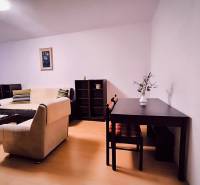 Living room in a two-room apartment with a wood-patterned floor, light couch, table.