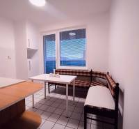 A kitchen with a corner bench, table, and window in a 2-room apartment.
