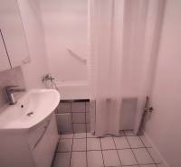 Bathroom in a 2-room apartment with a white sink, bathtub, and white tiles.