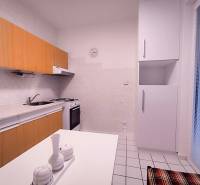 A kitchen in a 2-room apartment with tiles and light kitchen cabinets.