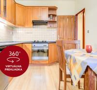 A kitchen in a 2-room apartment with a countertop, dining table, and floor with a wood decor.