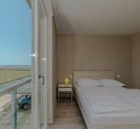 Bedroom in a holiday apartment with a view, bed, and wooden decor flooring.