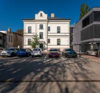 A parking lot with cars and a building on Južná trieda, Košice - Juh district.