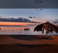 The photograph depicts a beach evening with palm trees and an award ceremony for the real estate agency Reality BICIAŇ.
