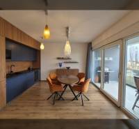 Dining area with wood-patterned flooring and large windows in a holiday apartment.