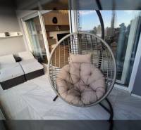 Relaxation terrace of a recreational apartment with a round hanging chair and rattan seating.