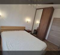 Recreational apartment with a comfortable bed and wooden decor flooring, illuminated by wall lamps.