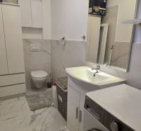 A bathroom in a holiday apartment with a washing machine and marble wall decor.