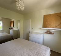 A bedroom in a family house with white furniture, a mirror, and textured bed covers.