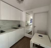 The kitchen area of a family house with white cabinets and a wooden decor floor.