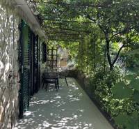 A terrace of a family house on the island of Čiovo, covered with vines, with a shower and garden furniture.