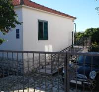A family house in Čiovo with a garden, a staircase, and a parked car at the entrance.