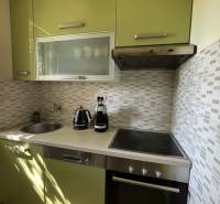 A kitchen in a family house with green cabinets, tiles, and built-in appliances.
