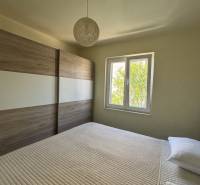 A bedroom in a family house with a French window and a large wardrobe.