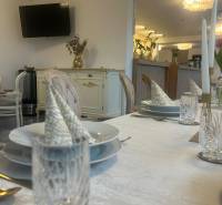 Set tables in a dining area with a television, golden decorations, and elegant table settings.