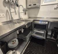 A kitchen in a gastro space with stainless steel sinks, appliances, and organized kitchen tools.
