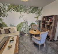 Interior of gastro spaces with plant wallpaper, comfortable furniture, and wooden decor.