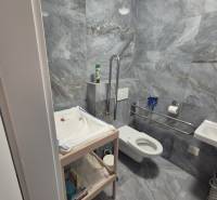 Gray bathroom tiles, changing table, and toilet in dining areas.