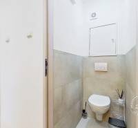 A toilet in the interior of a 3-room apartment with ceramic tiles and storage space.