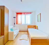 A room in a 3-room apartment with a wood-decor floor, furniture, and a large window.