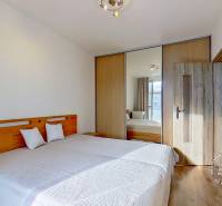 Bedroom in a 3-room apartment with a bed and a built-in wardrobe, floor with wooden decor.