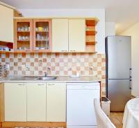 A kitchen in a 3-room apartment with tiles and light furniture, equipped with a refrigerator.