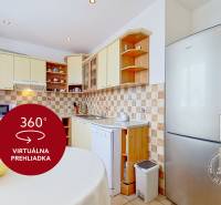 A kitchen in a 3-room apartment with built-in appliances, tiles, a spacious refrigerator, and a dining table.