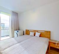 Bedroom in a 3-room apartment with a bed and a view through the balcony door.