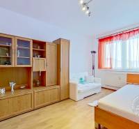 A room in a 3-room apartment with wood-decor furniture and a bed by the window.