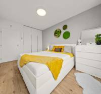 Bright bedroom with a bed, white furniture, plants, and wood-patterned flooring in a 4-room apartment.