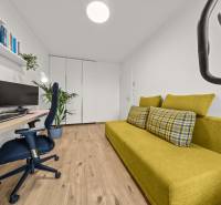 A room in a 4-room apartment with a green sofa, a computer, and a wooden decor floor.