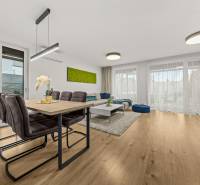 Dining and living area in a 4-room apartment with wood-patterned flooring.
